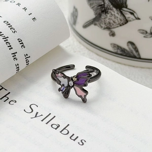 Détail d'une bague papillon vintage avec émail violet et zircons sur des pages de livre