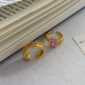 Dettaglio di due anelli vintage placcati in oro con zircone rosa su un libro aperto