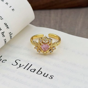 Dettaglio anello vintage in oro con zircone cuore rosa e incisione retrò su libro