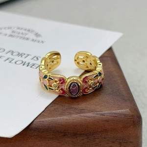 Détail d'une bague florale vintage en émail avec pierre violette et anneau doré ouvert