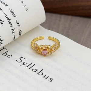 Dettaglio macro di un anello vintage dorato con zircone rosa su sfondo di un libro classico