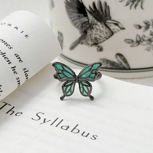 Détail macro de la bague papillon vintage avec émail sarcelle sur métal noir poli