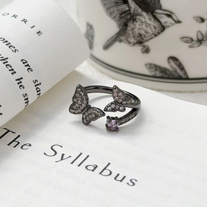 Détail d'une bague papillon vintage avec pierre violette sur des livres décoratifs