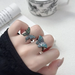Gros plan de deux bagues papillon punk vintage avec détail en émail dégradé vert