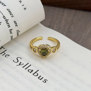 Dettagli dell'anello in oro con gemma a cuore verde e accenti di zircone sui lati