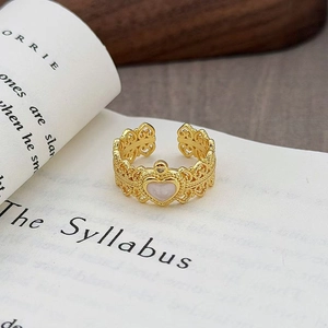 Dettaglio di un anello vintage dorato con cuore traforato su un libro aperto