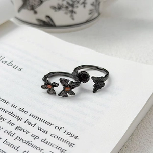 Détail de bagues papillon noires vintage avec zircon orange sur une page de livre