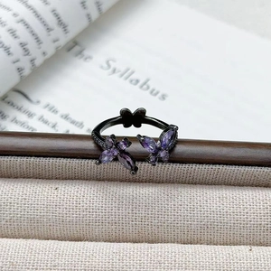 Détail d'une bague papillon noire gothique sertie de zircons violets sur livre vintage