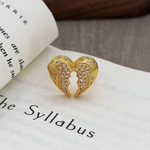 Dettaglio anello vintage a cuore dorato con zirconi su pagine di un libro aperto