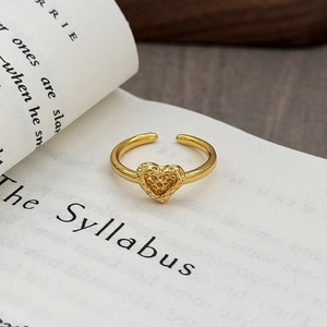 Dettaglio macro di anello a cuore dorato vintage con texture lavica su un vecchio libro