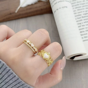 Dettaglio di anelli a cuore vintage con motivi in pizzo a corona e zirconi brillanti