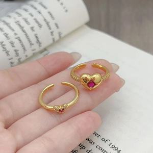 Dettaglio di anelli vintage a cuore in oro con rubini rossi e pavé su sfondo di libro