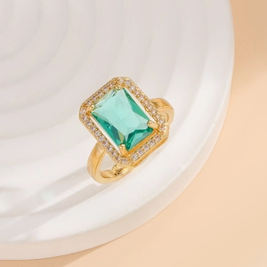 Macro view of emerald-cut green gemstone ring with pavé halo on gold setting