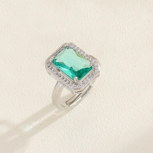 Macro detail of rectangle green emerald ring with white zircon halo and open band