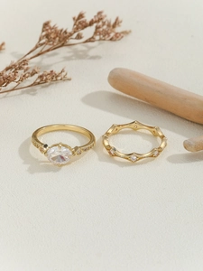 Close-up of gold bridal ring set with oval center stone and scalloped diamond band