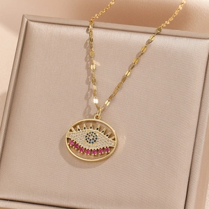 Macro shot of evil eye pendant with blue zircon stones and rose red gems on a gold chain