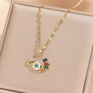 Detail of gold evil eye pendant with purple rhinestones and colorful enamel on satin
