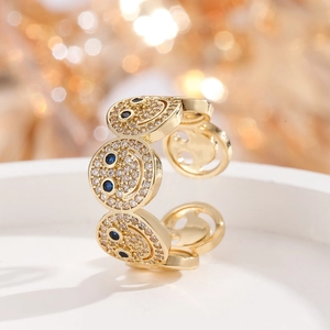 Makroaufnahme von vergoldetem Smiley-Ring mit Zirkonia-Pavé und blauen Edelstein-Augen
