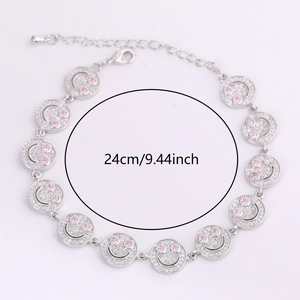 Detail of silver smiley face link bracelet with sparkling crystals and pink gem eyes