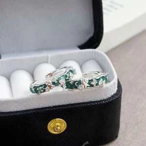 Détail de bagues émaillées chat et lune avec paillettes vertes sur une boîte à bijoux