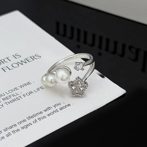 Detalle de anillo ajustable plateado con tres perlas y estrella de circón en tarjeta blanca