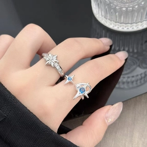 Detalle de anillos de estrella plateados con circonita brillante y gema azul en mano