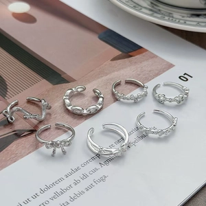 Dettaglio di un set di sette anelli minimalisti in argento con motivi a farfalla e fiori