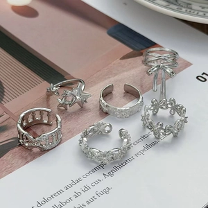 Set di 6 anelli geometrici argento con stelle, catene e motivi floreali su rivista