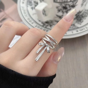 Dettaglio di un anello a fiocco argento multistrato indossato da una modella, stile vintage