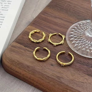 Detailansicht von vier Vintage-Ringen aus vergoldetem S925 Silber auf Holztablett