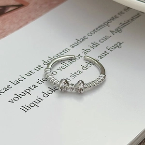 Dettaglio ravvicinato di un anello a fiocco argento con trama a spirale e zircone