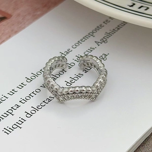 Dettaglio macro di anello d'argento ondulato con micro zirconi e design aperto regolabile