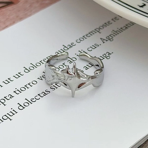 Dettaglio anello argento ondulato con motivo a stella centrale su un libro