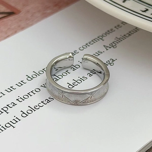 Dettaglio macro di anello regolabile argento con motivi geometrici e trama spazzolata