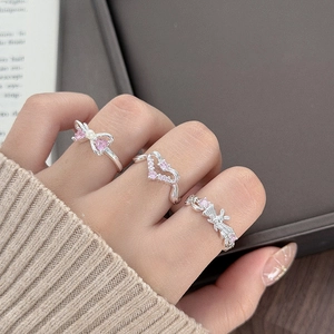 Detail of pink heart zircon rings with butterfly ribbon motifs on model fingers