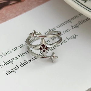 Dettaglio anello a spirale argento con motivi a stella e pietra di zircone rosso