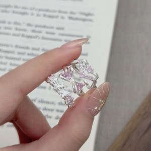 Detailed view of three silver rings featuring pink zircon butterfly and heart motifs