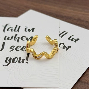 Detail eines goldenen Wellenrings mit drei Zirkonia-Steinen und Spiegelglanz-Finish