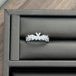Detailed view of silver butterfly ring with pink zircons on black velvet box
