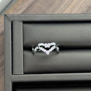 Macro shot of silver wave heart ring with pink zircon and diamonds on grey velvet box