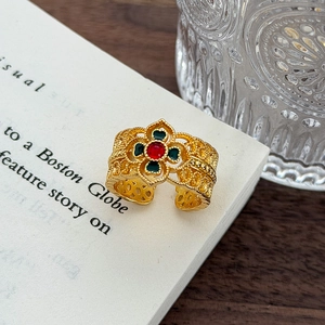 Dettaglio dell'anello dorato traforato con smalto rosso e verde su libro antico