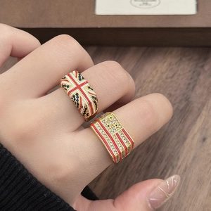 Detail van vintage emaille vlagringen in goudkleur met zirkoon inleg op de hand