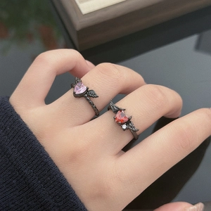 Gothic wings heart rings with pink and red gemstones shown in a close-up on fingers