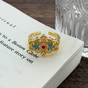 Dettaglio macro di anello vintage in smalto con gemma rossa e motivi floreali