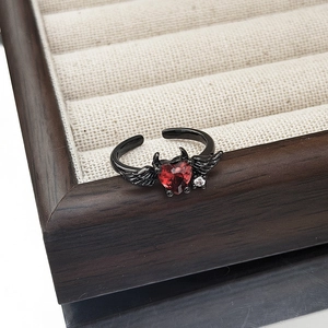 Detail of gothic heart ring with red gemstone and black devil wings on jewelry display