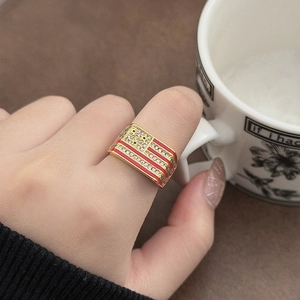 Macro-opname van vergulde ring met Amerikaanse vlag, zirkonen en emaille aan de hand