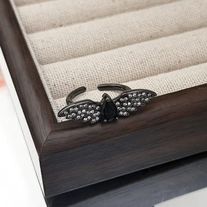 Macro shot of gothic wing ring with a black pear-shaped gemstone on a wooden tray