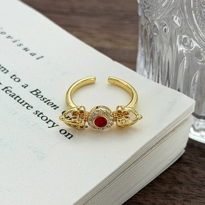 Vista macro di anello d'oro retrò con pietra rossa e design Vajra su un libro