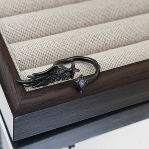Detail of gothic wing ring with purple teardrop zircon and black plating texture