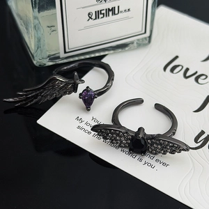 Macro shot of gothic wing rings with black and purple pear-cut gemstones in dark metal